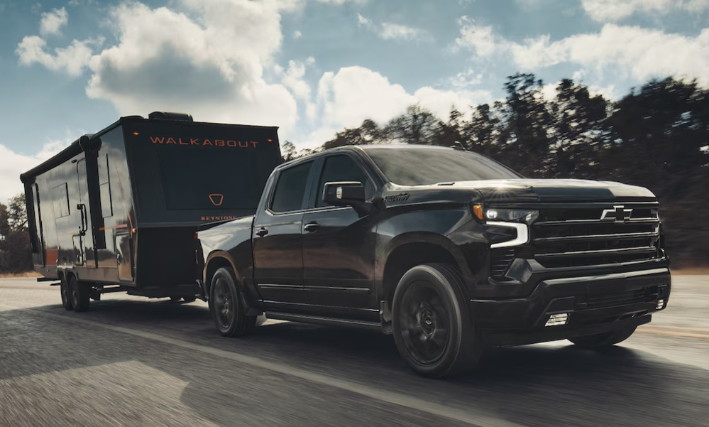 A black 2026 Chevrolet Silverado 1500 truck towing a trailer