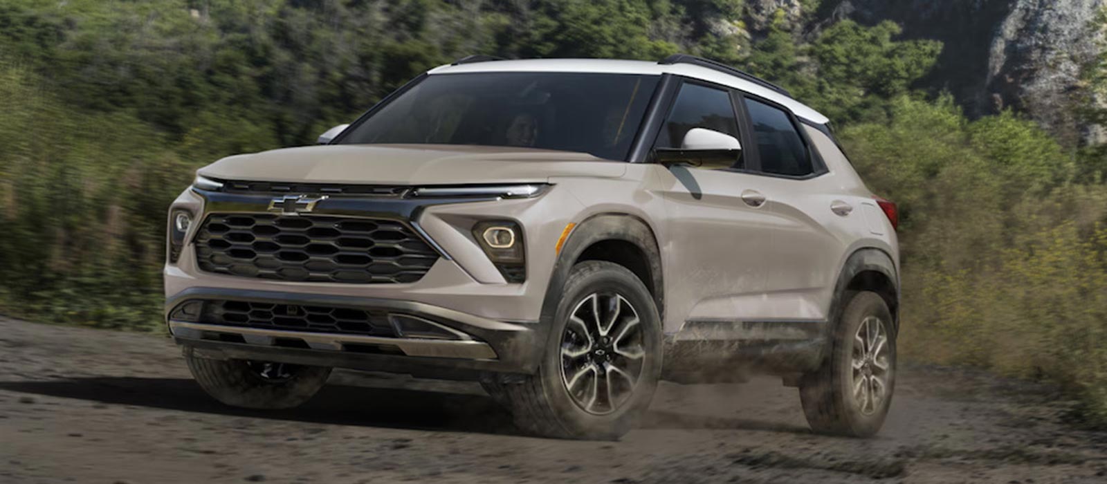 A beige 2026 Chevrolet Trailblazer SUV driving down a muddy road