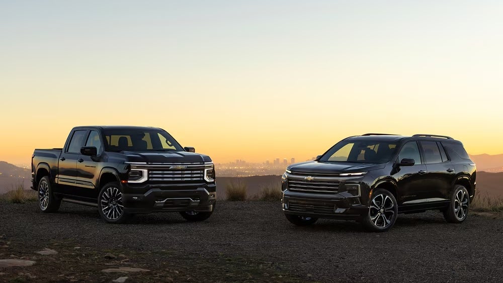 A black Chevrolet truck and SUV at sunset