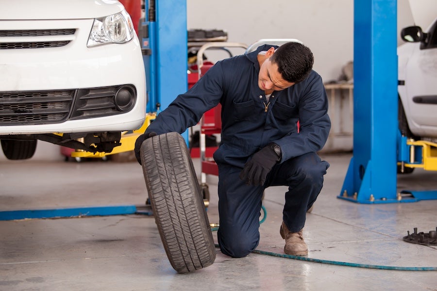 A mechanic inspecting the tire of an elevated car